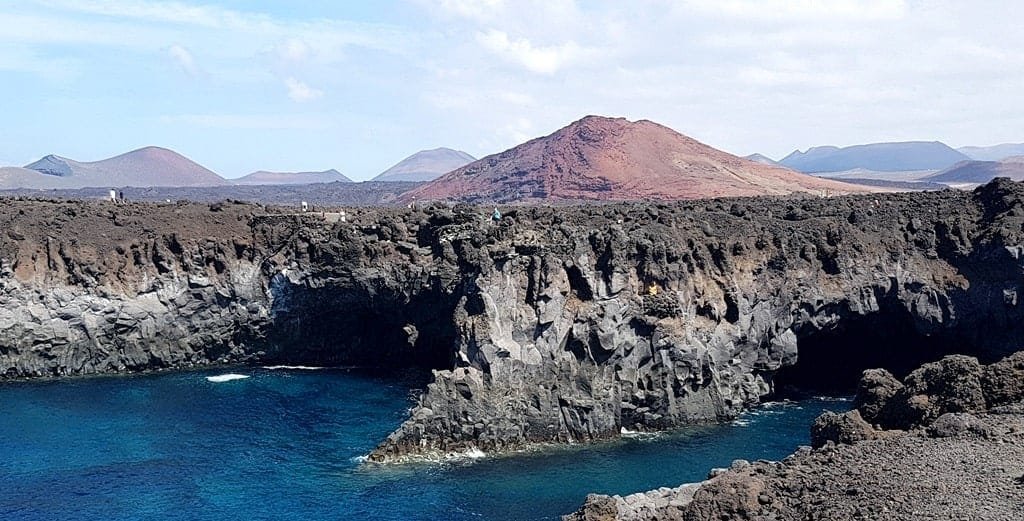 Los Hervideros and the volcanoes in the background